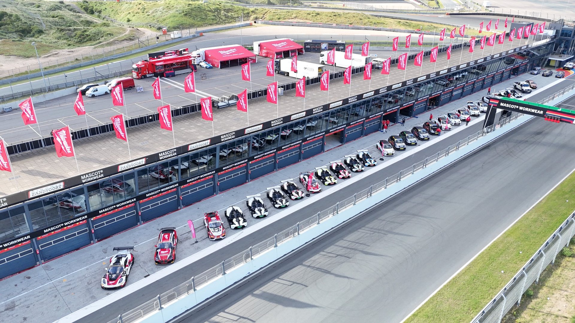 Luftaufnahme eines Firmenevents am Circuit Zandvoort mit Boxengasse, Fahrzeugflotte und Eventbranding